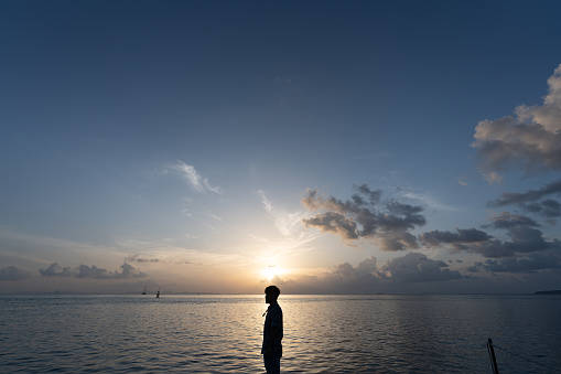 Man stand on pier inthe sea with sunrise scene above his head / thinking concept / human knowledge / design thinking / work on holiday