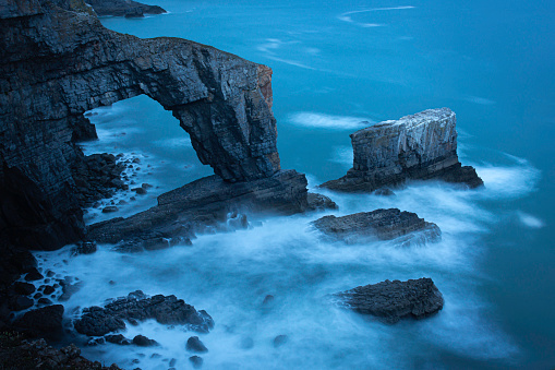 Green Bridge of Wales, famous rock formation and iconic landmark on dramatic Pembrokeshire coast, South Wales, Uk, photographed at twilight.Long exposure image.