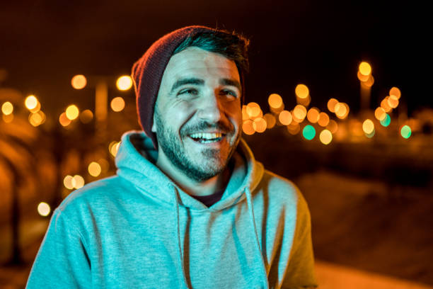 istock Man laughing and wearing casual clothes and a wool hat at night 1168216270