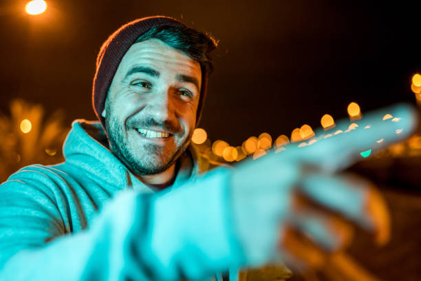 Man laughing and wearing casual clothes and a wool hat at night stock photo