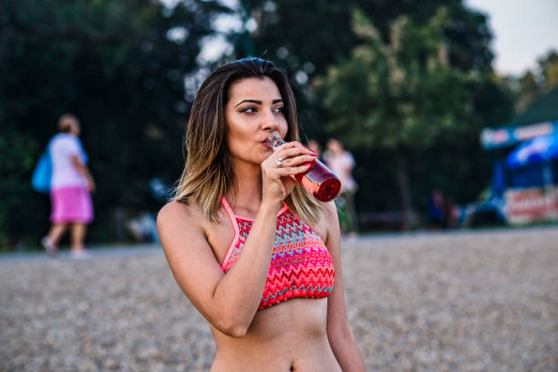istock Young Attractive Woman at the Beach is Refreshing with a Cold Drink 1168218480