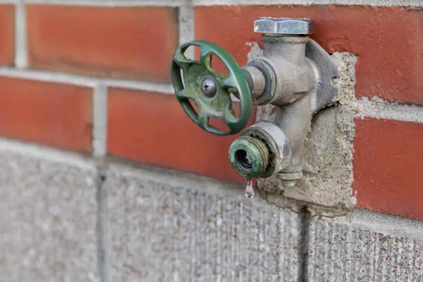 Photo of old, corroded outdoor water spigot, tap, faucet leaking and dripping water in need of repair