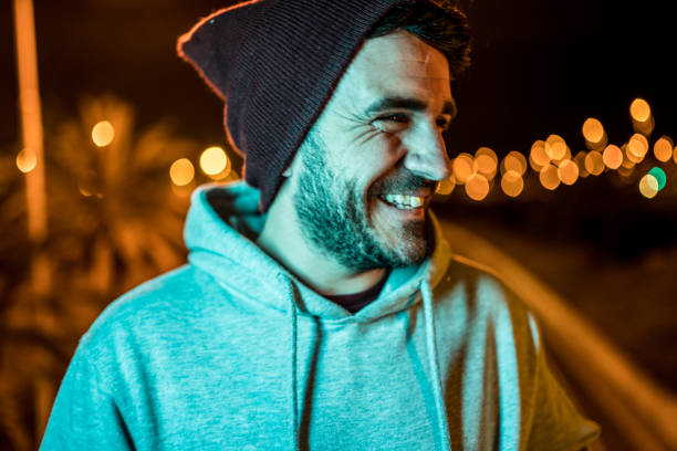 istock Man laughing and wearing casual clothes and a wool hat at night 1168220774