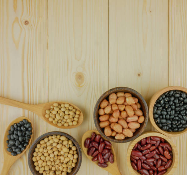 Flat lay,top view assorted beans including red bean,soybeans,black beans,mung beans on brown,beige wooden background with copy space