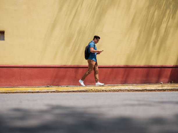 Male walking on the side walk Male, Millennial, Smart Phone, Traveler, Latin, Tourist, mexico street scene stock pictures, royalty-free photos & images