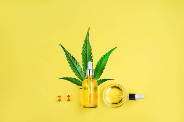 Bottle with CBD oil, pipette, capsules and cannabis leaf on a yellow background. Minimalism, flat lay. Bottle with CBD oil, pipette, capsules and cannabis leaf on a yellow background. Minimal composition, flat lay cannabidiol photos stock pictures, royalty-free photos & images