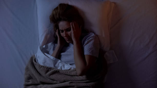 istock Young lady holding head in bed, suffering headache after awakening at night 1168236282