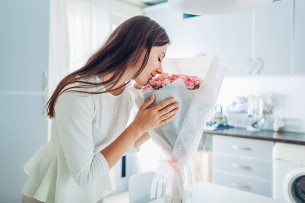 kobieta pachnący bukiet róż. gospodyni korzystających wystrój i wnętrze kuchni. słodki dom - flower gift decoration domestic room zdjęcia i obrazy z banku zdjęć