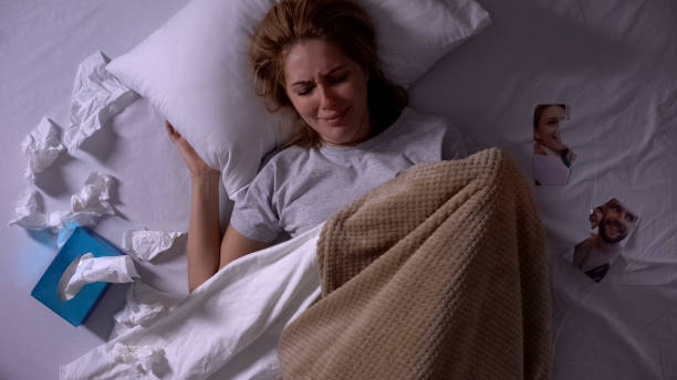 Woman crying lying in bed with tissues, torn photo of ex-boyfriend beside, break Woman crying lying in bed with tissues, torn photo of ex-boyfriend beside, break former stock pictures, royalty-free photos & images
