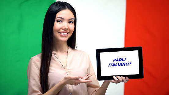 Woman holding tablet with do you speak italian phrase, app for learning language