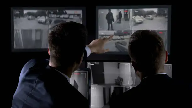 Photo of Private agents monitoring CCTV footage, searching for criminal, discussion