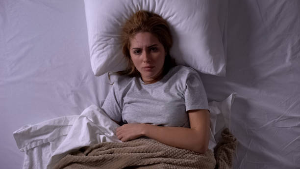 istock Lady feeling unwell lying in bed covered with blankets, menstrual pain, topview 1168238039