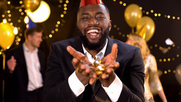 istock Glad african american holding gold confetti and smiling at camera, celebration 1168238251