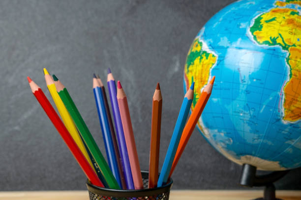 istock Colored pencils and a globe on the background of the blackboard 1168240892