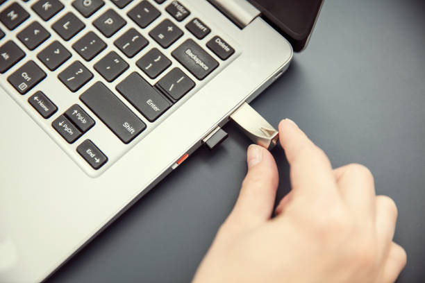istock Woman's hand connects design aluminium pendrive to modern ultrabook. 1168248102