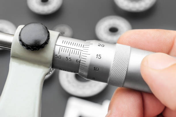 Hand holding micrometer over workplace with bearings. Hand holding micrometer over workplace with bearings. micrometer screw gauge stock pictures, royalty-free photos & images