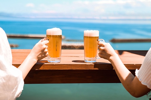 Two females enjoy drinking beer in front of sea