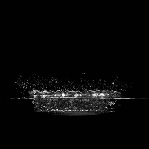 Isolated puddle splash Dramatic isolated puddle splash side view in black and white water on black surface stock pictures, royalty-free photos & images