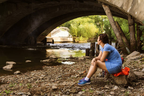 istock woman smokes while sitting alone under a bridge 1168252670