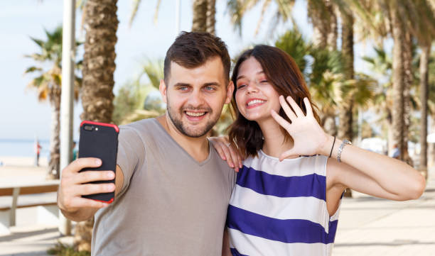 istock Happy man and girl standing and taking selfie 1168254825