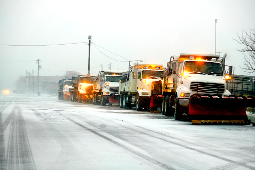 Snow plows in severe blizzard preparing for storm clearing street driving