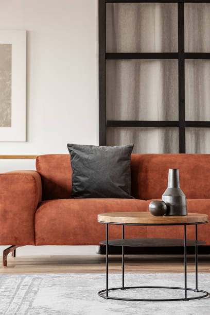 istock Black vase on wooden coffee table in chic living room interior with comfortable sofa 1168259940