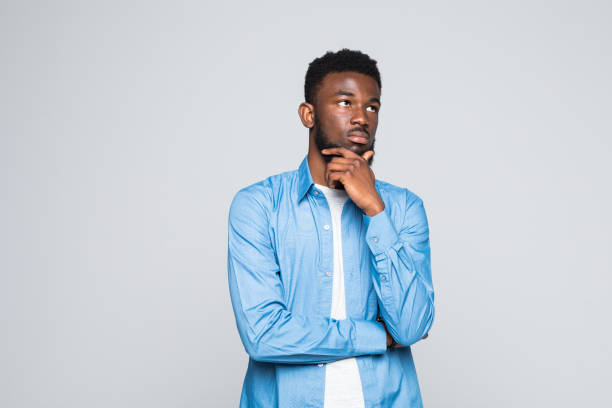 istock Closeup portrait handsome african man looking up sideways dreaming, remembering good times hand on chin, isolated on white background. Positive human emotions, facial expression, feelings 1168263780