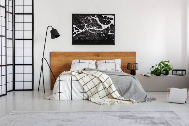 istock Black map on white wall above wooden headboard in simple bedroom interior 1168267364