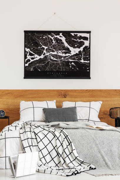 istock Black map on white wall above wooden headboard in simple bedroom interior 1168267367