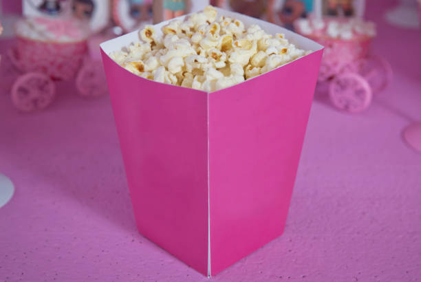istock Popcorn spilled from a striped box . Three vintage-style boxes of popcorn in a carnival themed still life with arcade game pink tickets 1168269846