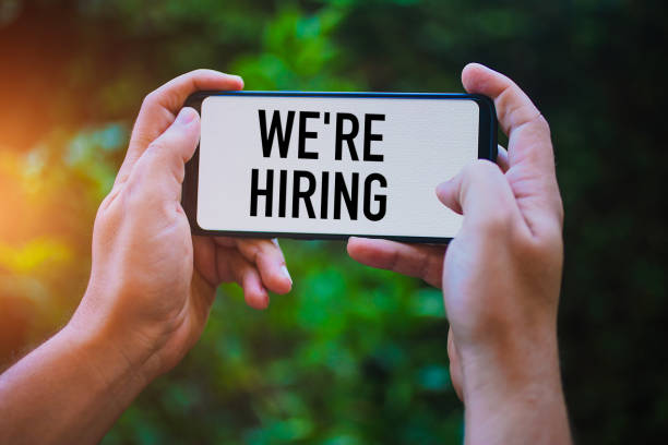 istock Two hands holding modern smartphone with the text : We're Hiring 1168271635