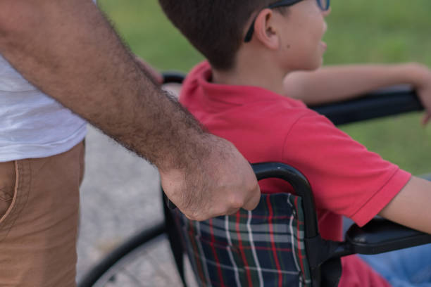istock Father walking with disabled son in park 1168280157