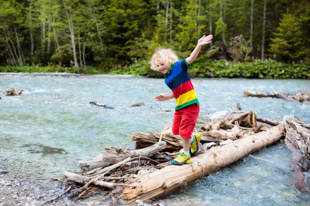 Child hiking in mountains. Kids at river shore.