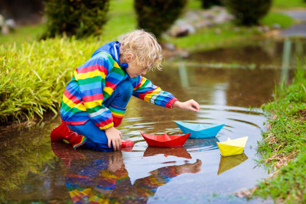 istock Child with paper boat in puddle. Kids by rain. 1168286482