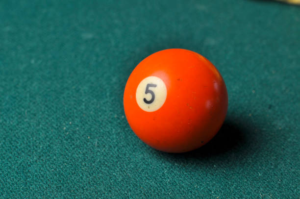 istock Old billiard ball number 5 orange color on green billiard table, copy space 1168287129