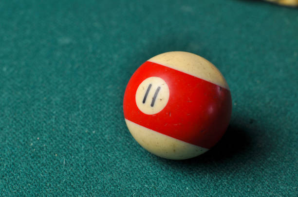 istock Old billiard ball number 11 striped white and red on green billiard table, copy space 1168287165