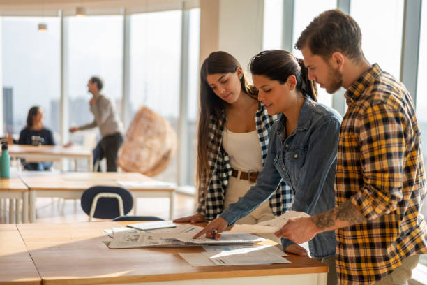 istock Female team leader talking to coworkers while pointing at some documents all very focused at the office 1168290371