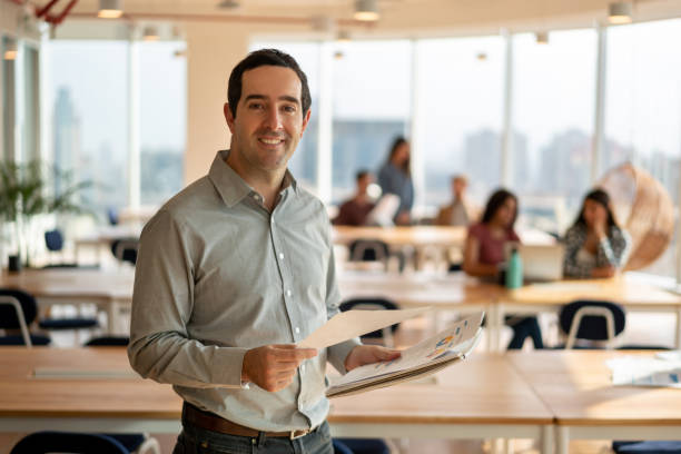 istock Adult bussiness man holding documents while facing camera very cheerfully 1168290372