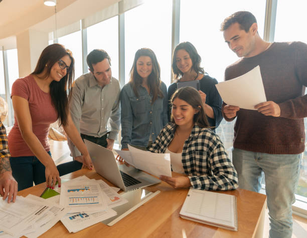 istock Young people working together at a coworking office looking at documents and laptop smiling 1168290498