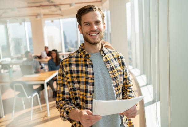 istock Handsome young casual businessman at a coworking office holding a document while smiling at camera 1168290538