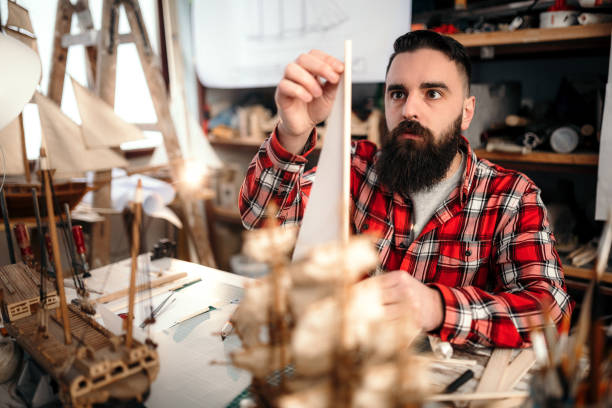 istock Bearded man making sailboat in his garage for hobby 1168296119