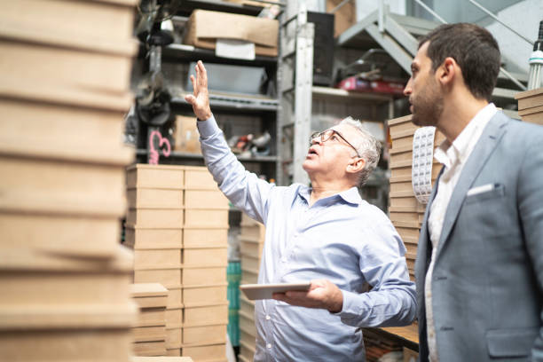 istock Senior and young business owner checking products in a storage room, using digital tablet 1168298625