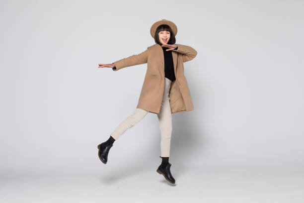 istock Charming young woman wearing a coat jump isolated over white background. 1168302392