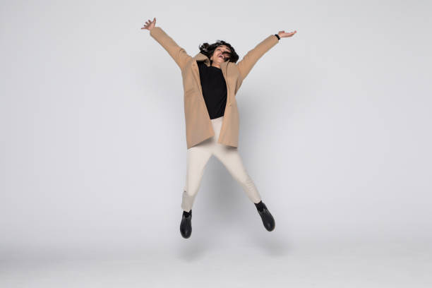 istock Young pretty girl jumping in beige coat isolated on white background 1168304424