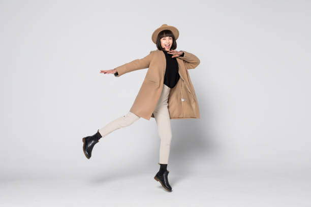 istock Young pretty girl jumping in beige coat isolated on white background 1168304468