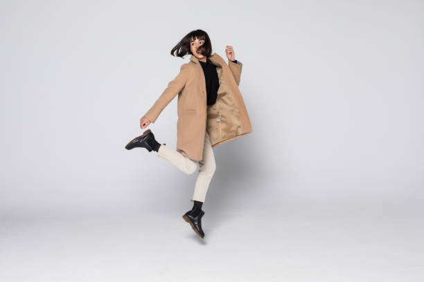 istock Young pretty girl jumping in beige coat isolated on white background 1168304516