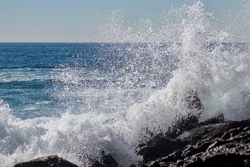 Large powerful wave crashing on to a rocky cliff on a California beach.