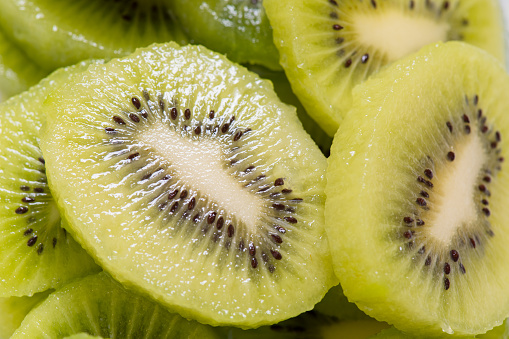 Many kiwi slices are placed in a glass crisper. Kiwifruit slices without peel,