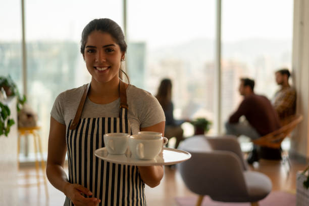 istock Beautiful waitress at a coworking office space holding a tray with a coffee order smiling at camera 1168307445
