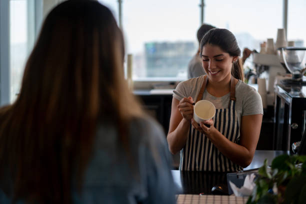 istock Beautiful woman working at a cafeteria writing a message on a take out coffee cup for unrecognizable customer 1168307489